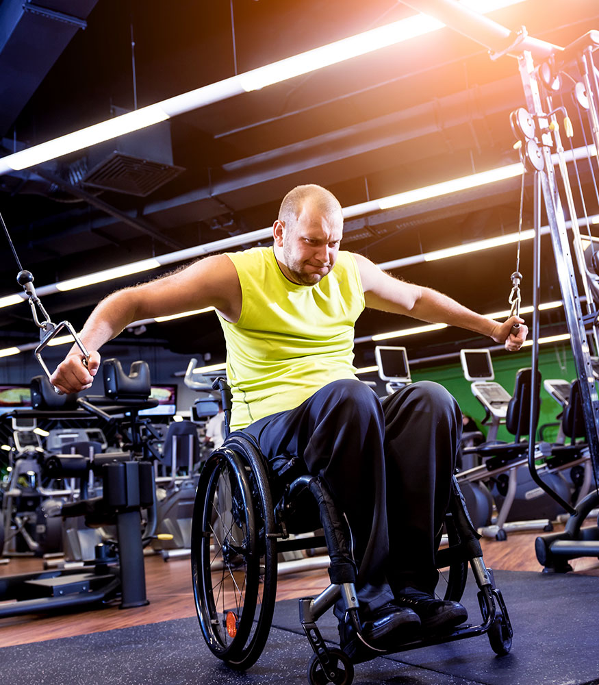A wheelchair user training on a cable machine in the gym