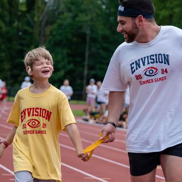 A coach running alongside a young athlete on a track