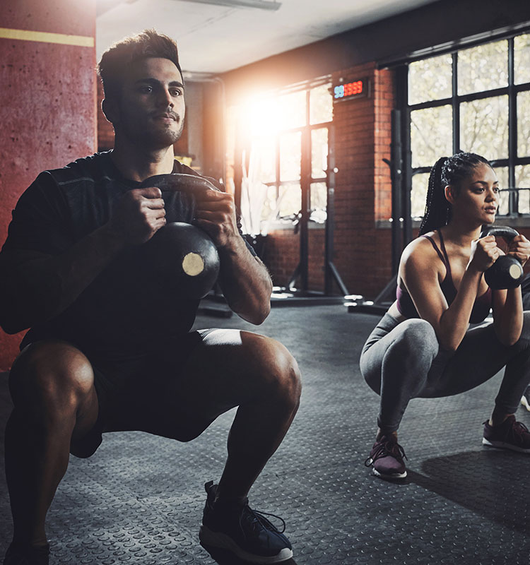 Two members performing kettlebell squats during a group training class