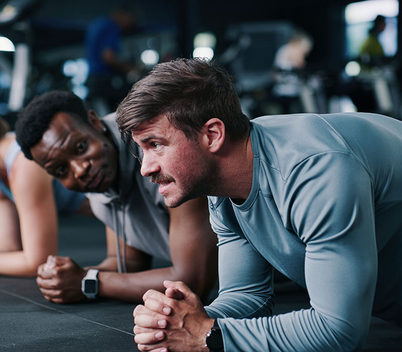 Two members training together in a plank position during a group class at Wallace Fitness Center