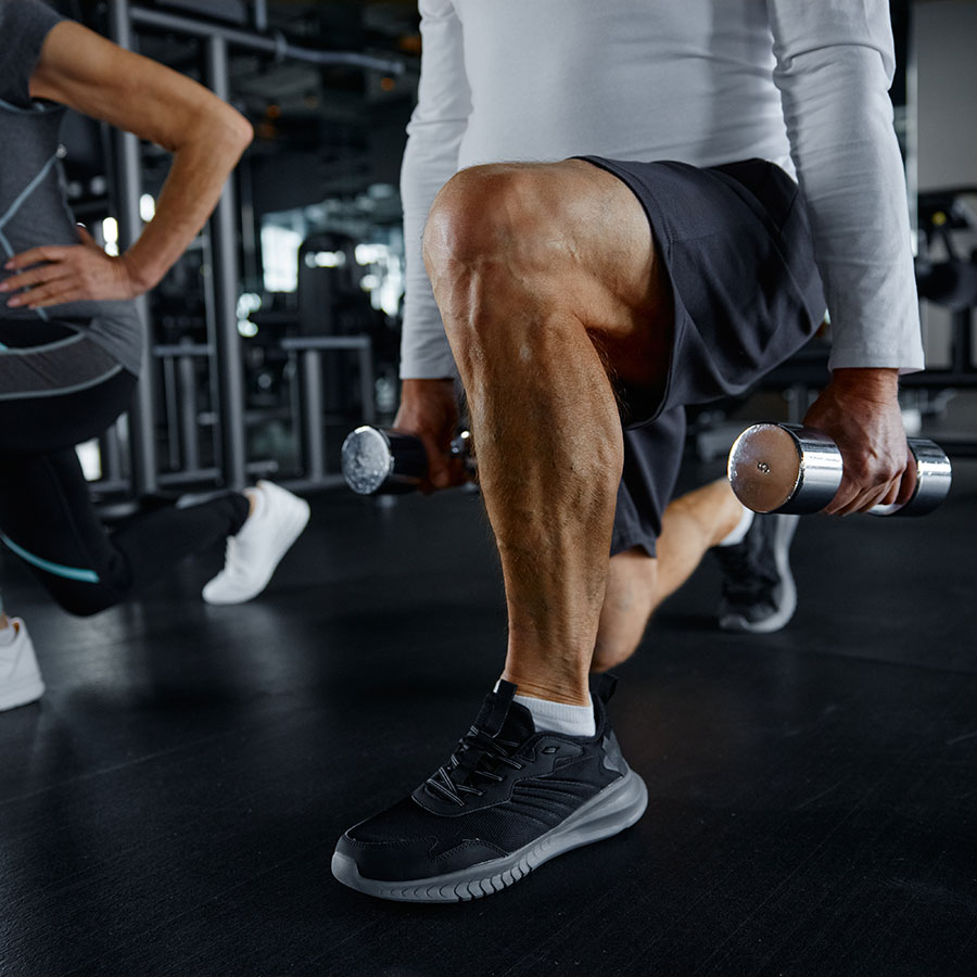 A member performing dumbbell lunges during a group training session