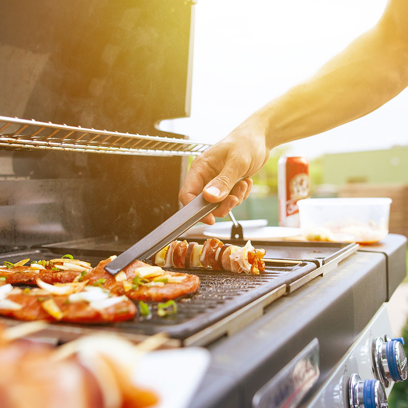 Meat and vegetable skewers cooking on an outdoor grill